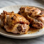 Golden brown air fryer chicken thighs served on a white plate